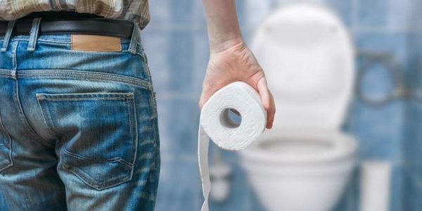 Ein Mann mit dem Toilettenpapier in der Hand vor der Toilette.